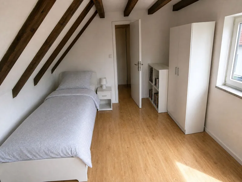 Einzelzimmer unter Dachbalken mit Bett und Schrank