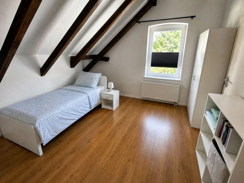 Einzelzimmer unter der Dachschräge mit Bett, Regal und Fenster